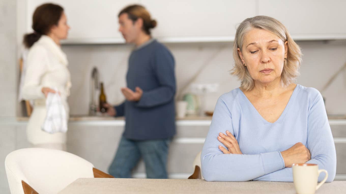 Mother-in-law sitting in front of adult couple arguing about bills. 