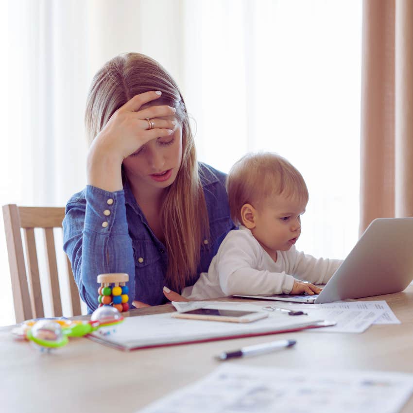 overwhelmed mom holding baby while sitting in front of computer