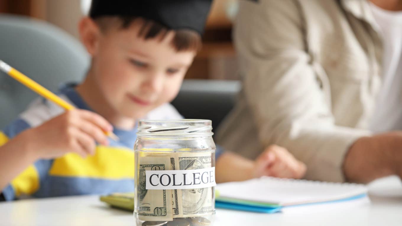 little boy sitting with silhouette of parent wearing graduation cap in front of jar of college savings