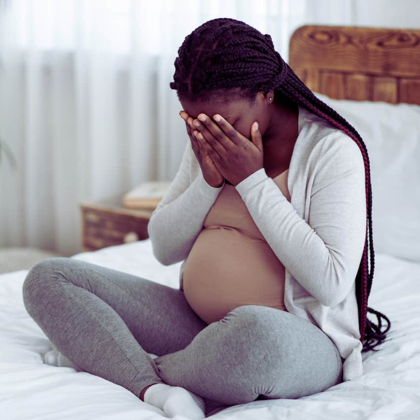 sad pregnant woman with her hands covering her face