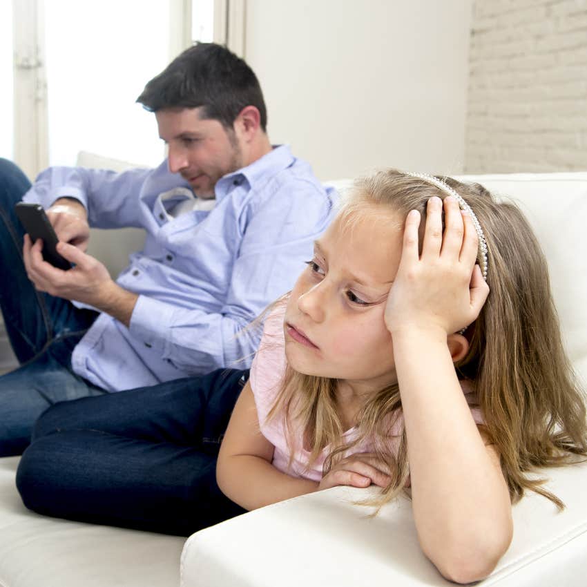 Narcissist parent looking at phone next to young daughter. 