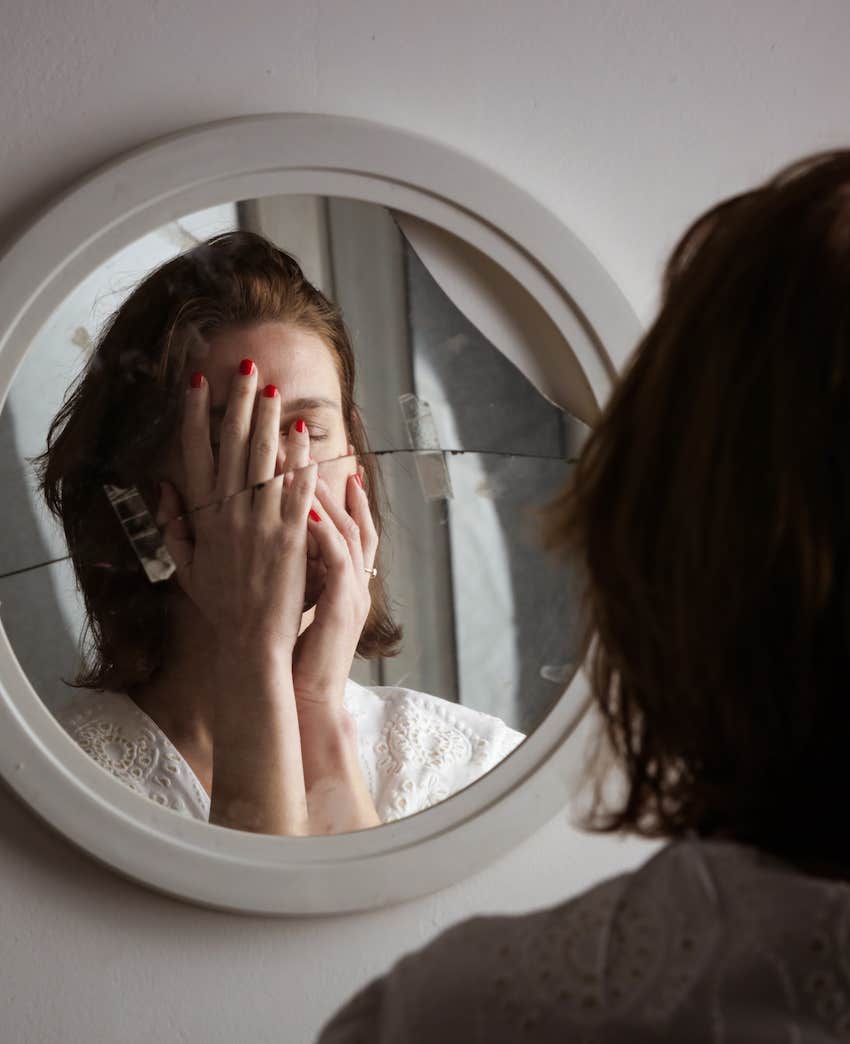 Woman looks in broken mirror we can't see her rage