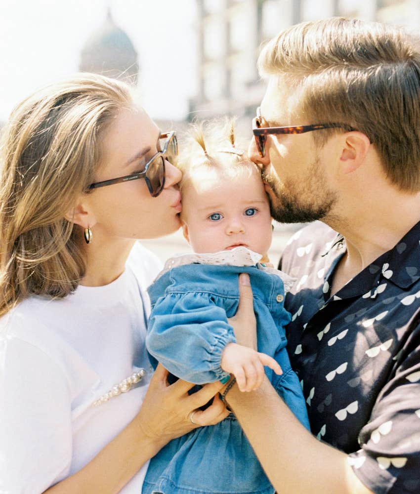 mom and dad kissing baby