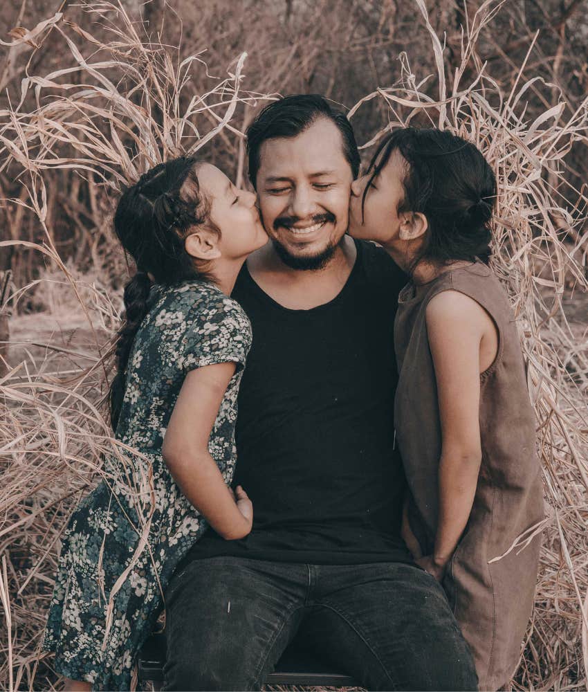 two kids kissing their dad on the cheek