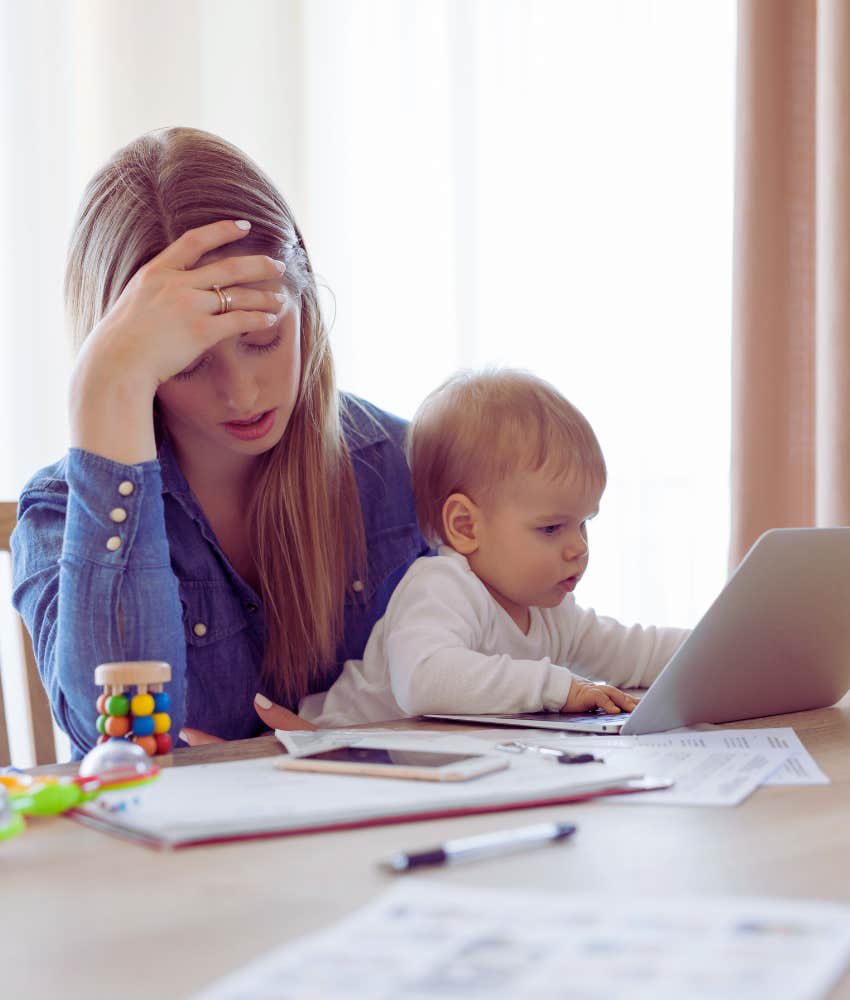 single mom holding baby trying to pay bills online