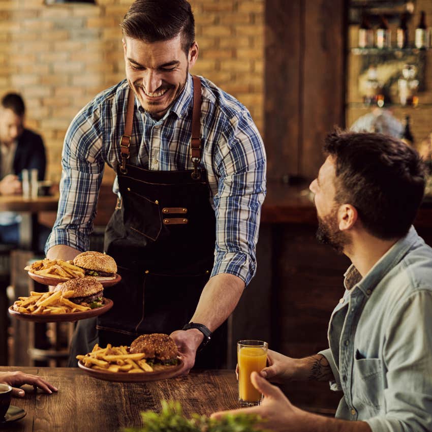 Waiter serving chef's food to a table at a restaurant. 