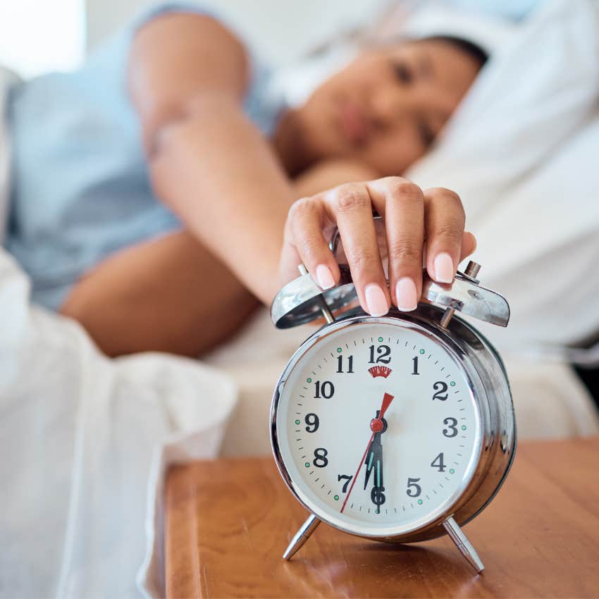 Woman waking up from dreams with an alarm clock. 