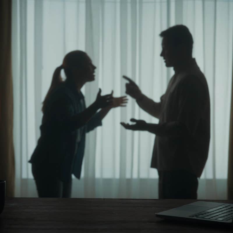 Silhouette of man and a woman arguing in the living room near the window