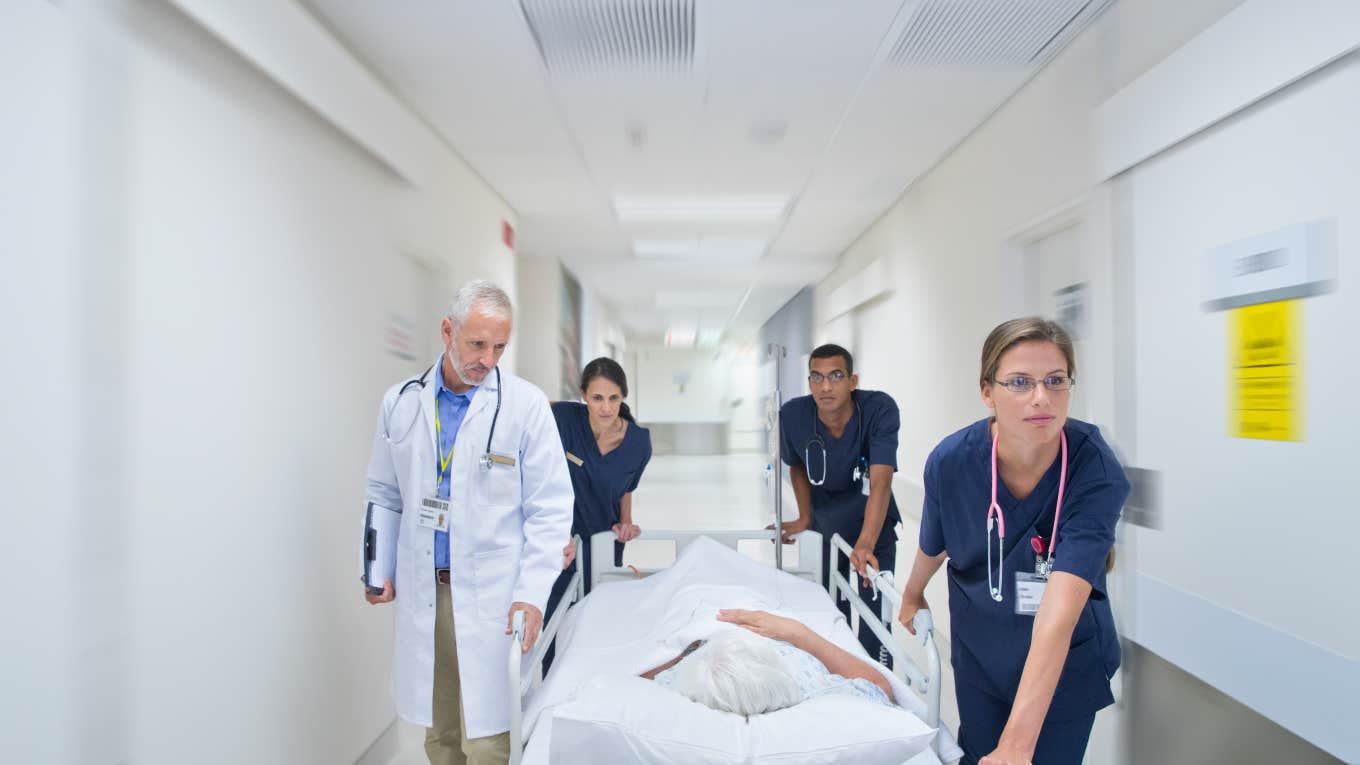 person being wheeled down a hospital hallway in bed by medical team