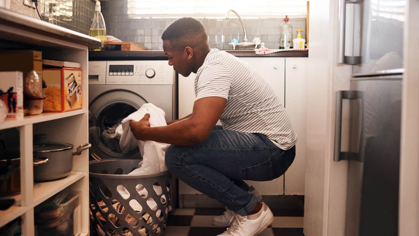 man putting laundry in washing machine