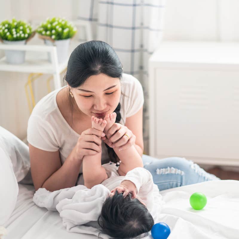 mother holding baby's feet and kissing them