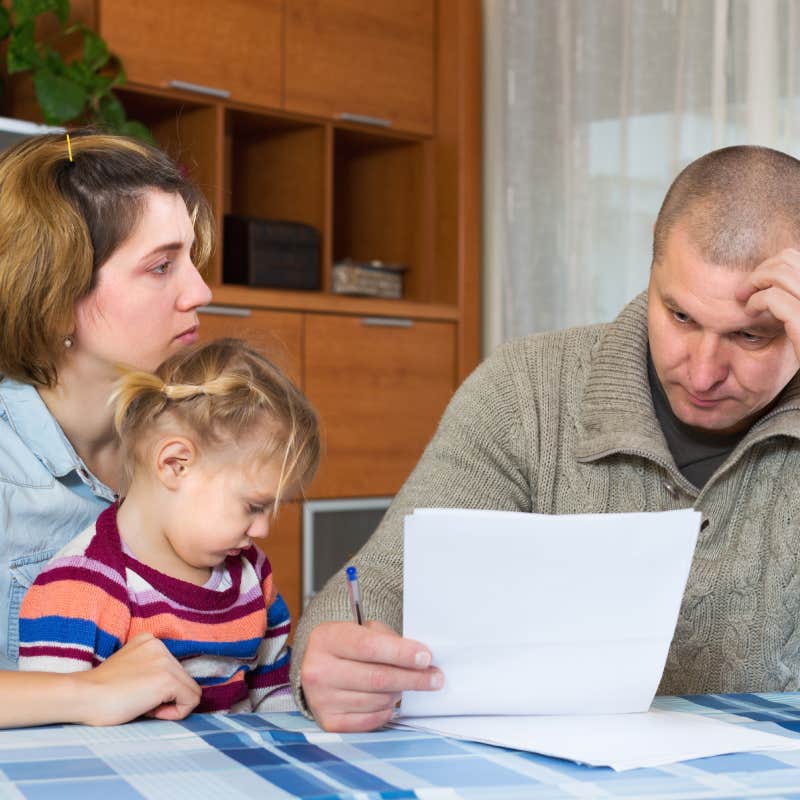 stressed couple looking at bills with little girl on mom's lap