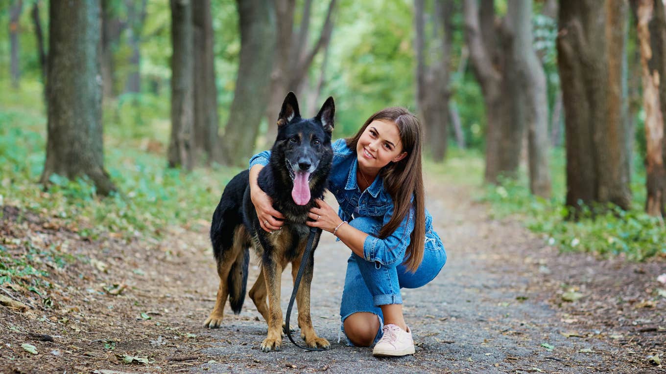 woman holds her german shepherd on nature trail