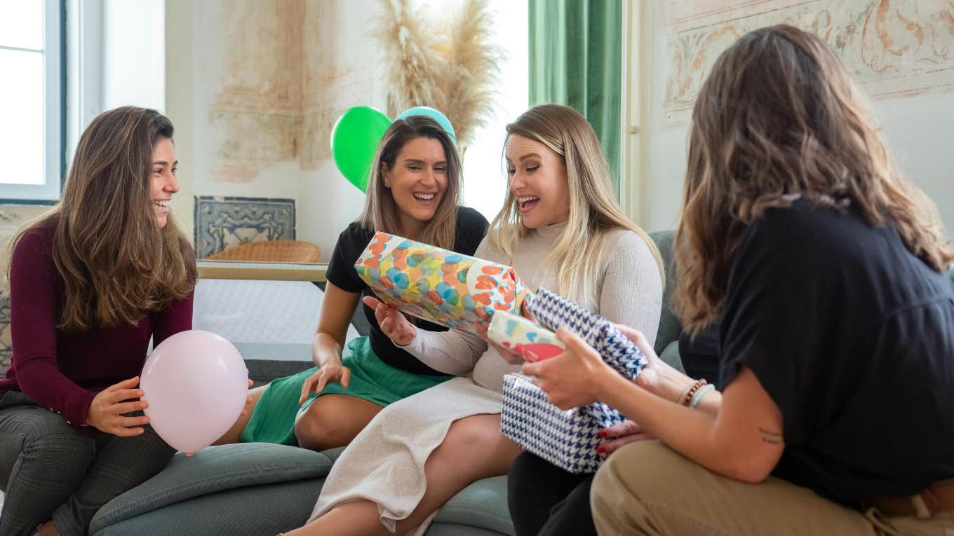 group of friends handing out gifts at baby shower to mom-to-be