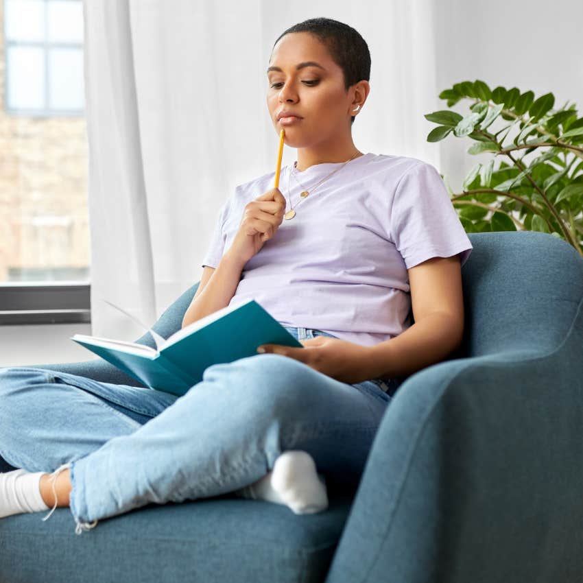 Woman sitting on her couch journaling. 