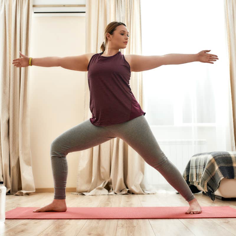 curvy woman in sportswear practicing yoga on a mat at home