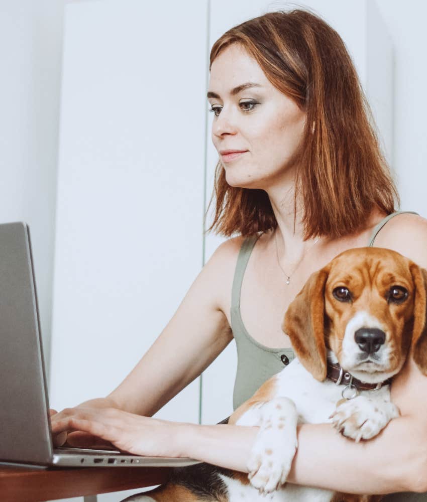 Woman working from home with her dog in her lap