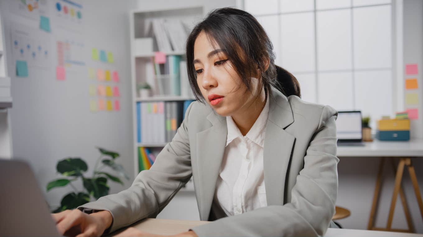  overworked and tired businesswoman sitting at desk with laptop