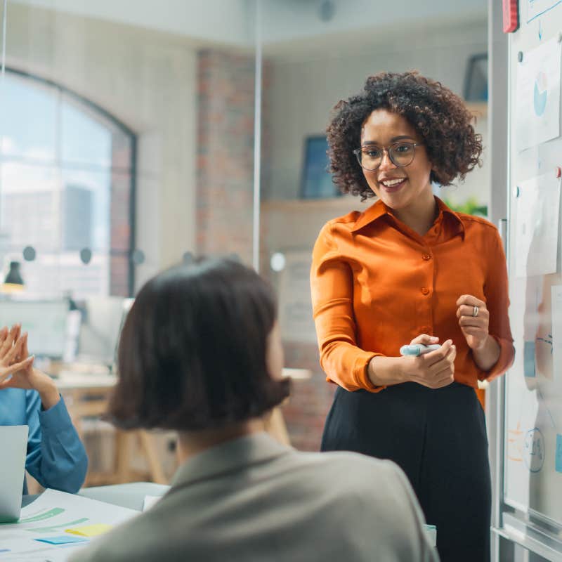 black female employee making presentation in office to coworkers