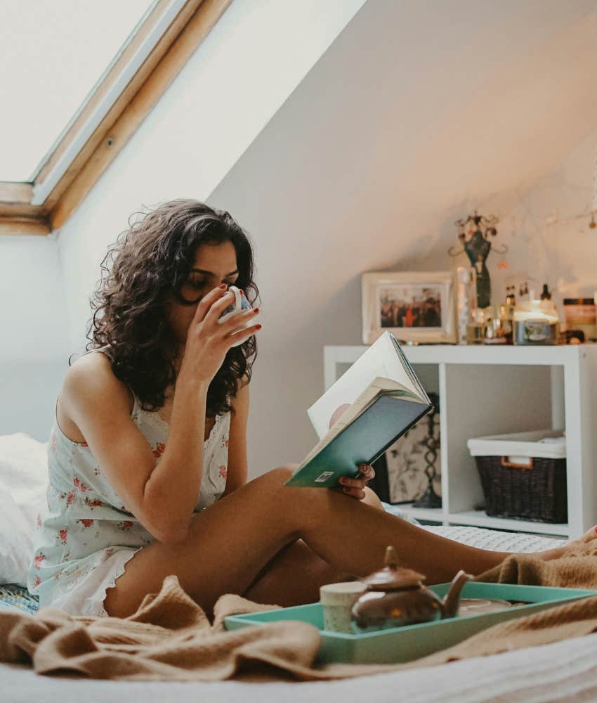 woman reading and drinking tea in bed