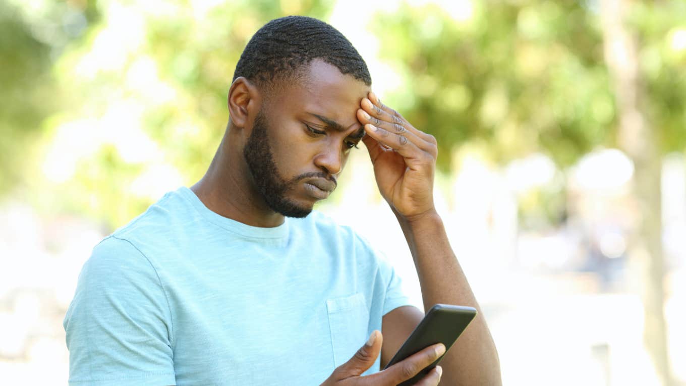 man looking at phone with concern outside