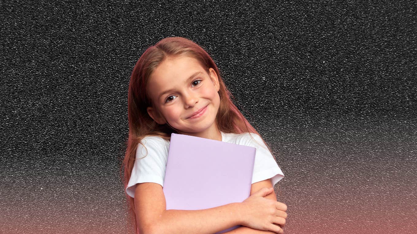 little girl holding a diary looking silently at the camera