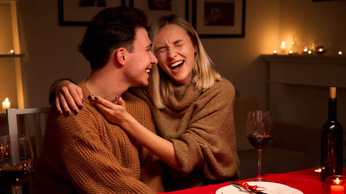 couple laughing and embracing each other during romantic dinner