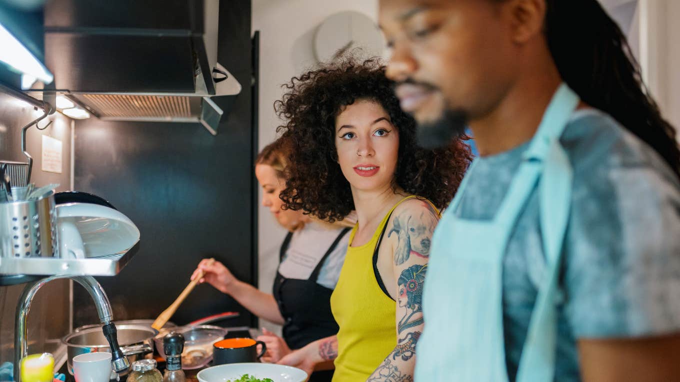 woman glances over at roommate while cooking meal together in kitchen