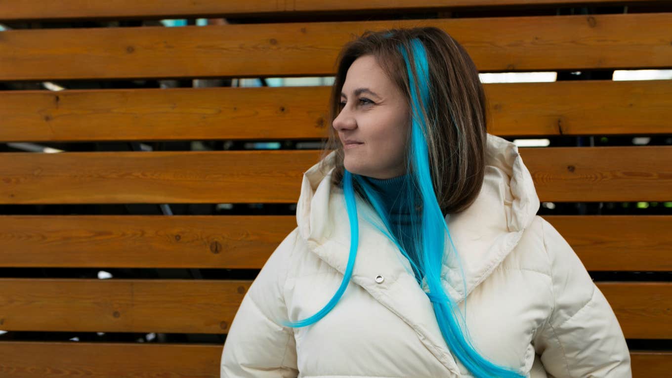 confident woman with blue strands of hair sitting outside