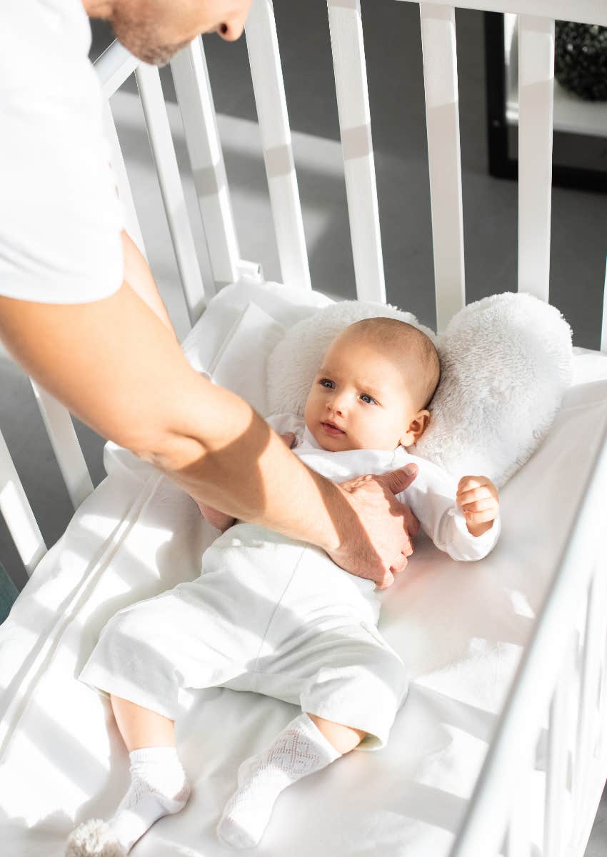 Dad putting baby in crib