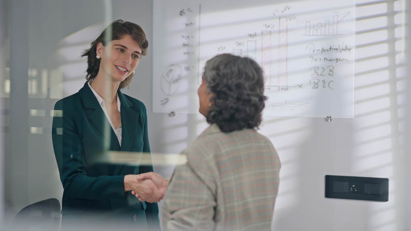 female business partners shake hands during meeting in workplace