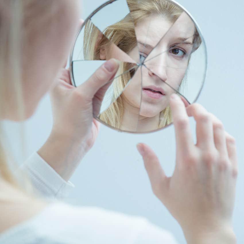 Woman looking in broken mirror