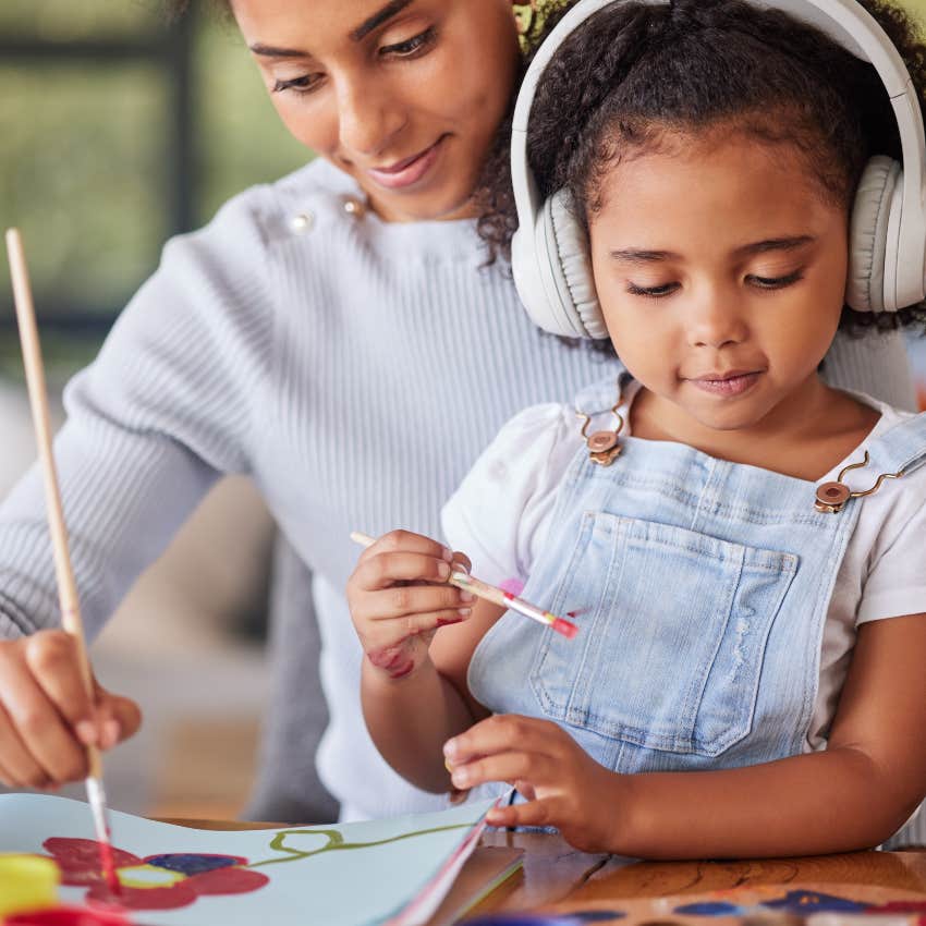 child with autism wearong headphone painting with woman