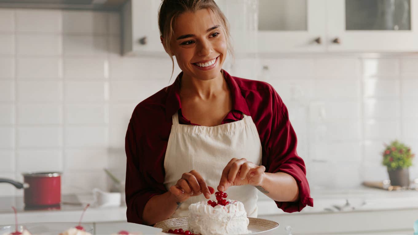 Woman decorating a cake in her bakery kitchen. 