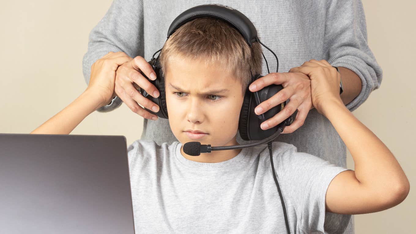 Mother taking headphones off her angry son playing video games