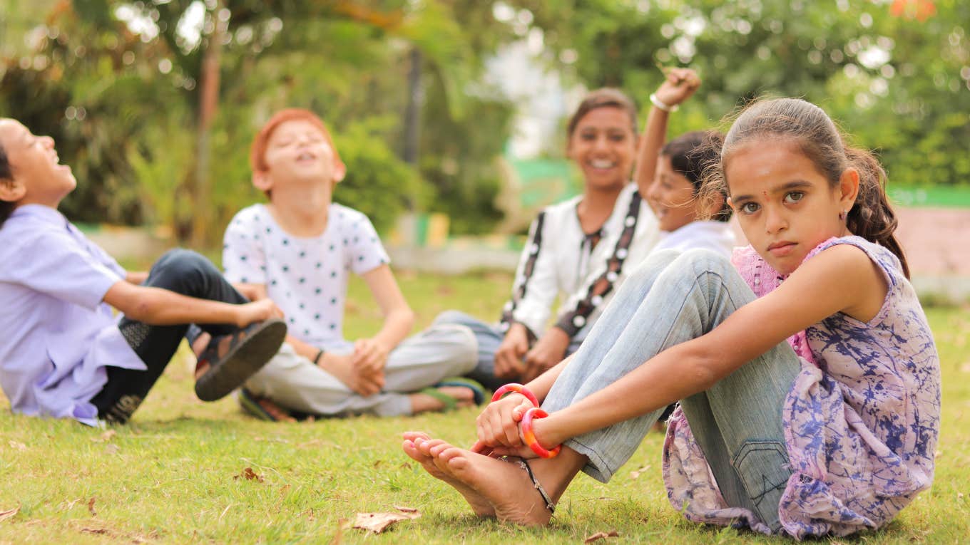 little girl sitting apart from other kids