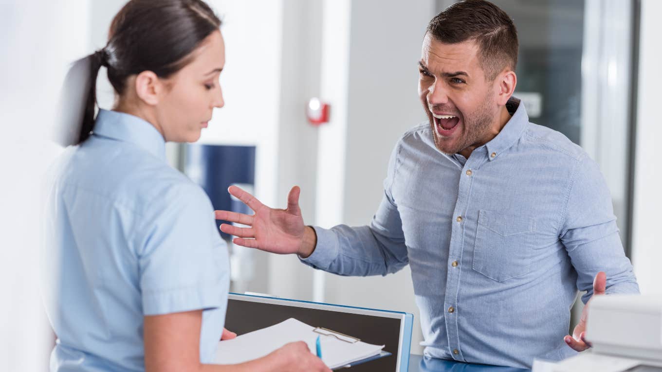 man yelling at a woman behind a desk