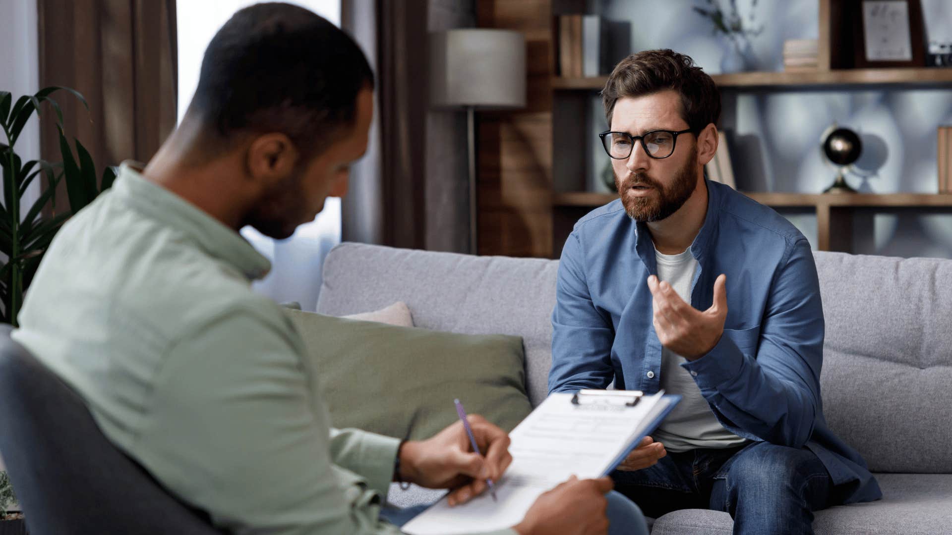 therapist looking writing down notes while patient stares at therapist