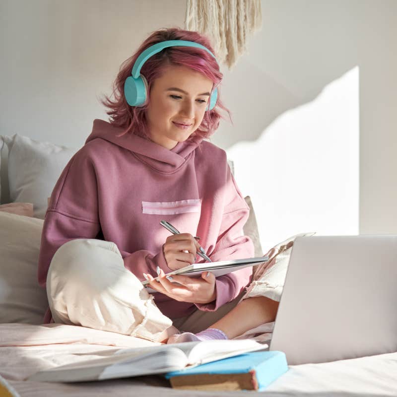 student wearing headphones studying with notebook and laptop