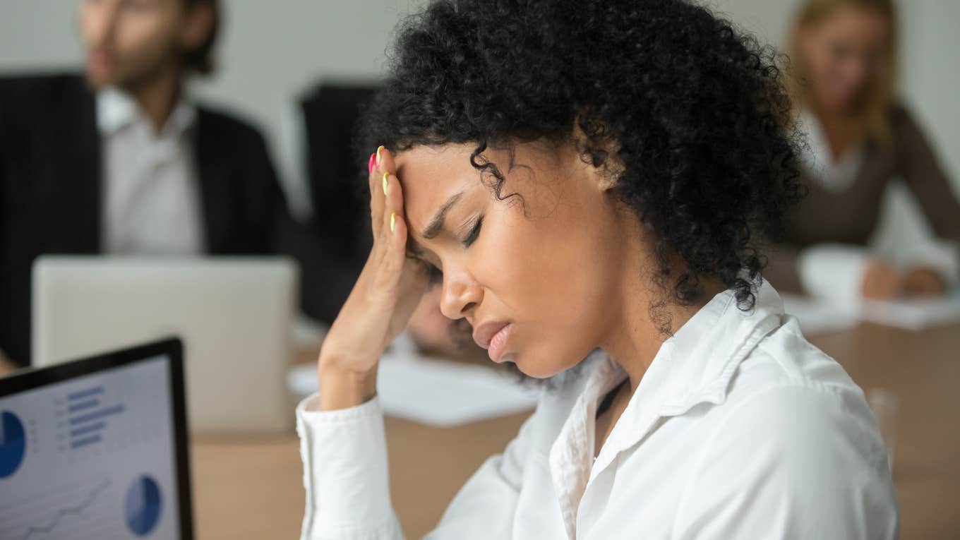 businesswoman feeling unwell from headache touching forehead at team meeting