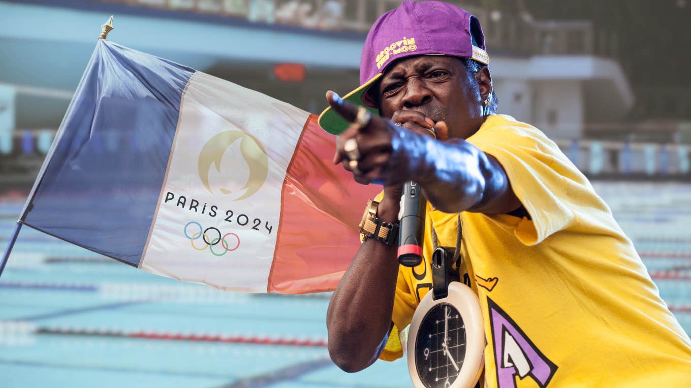  Flavor Flav standing in front of water polo team pool and Olympics flag.