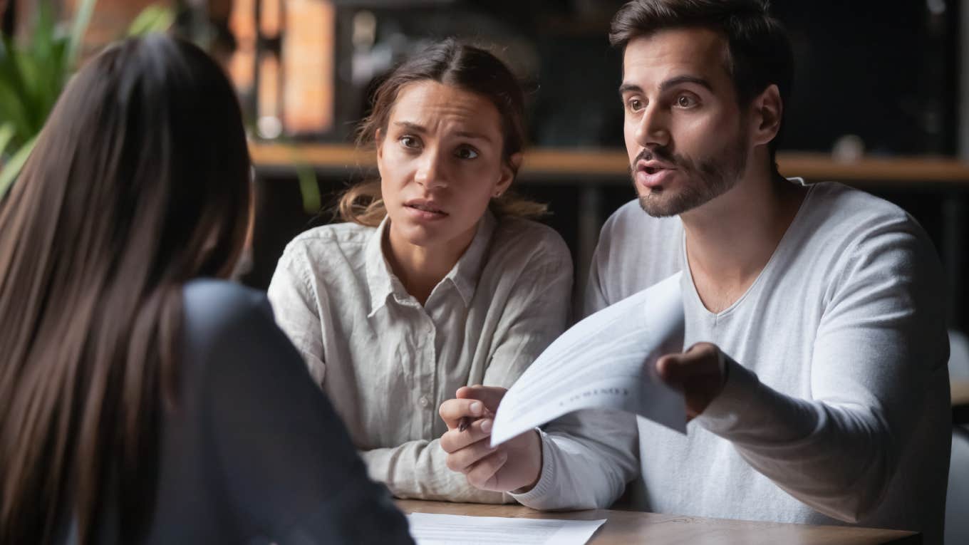 angry couple holding papers while talking to manager