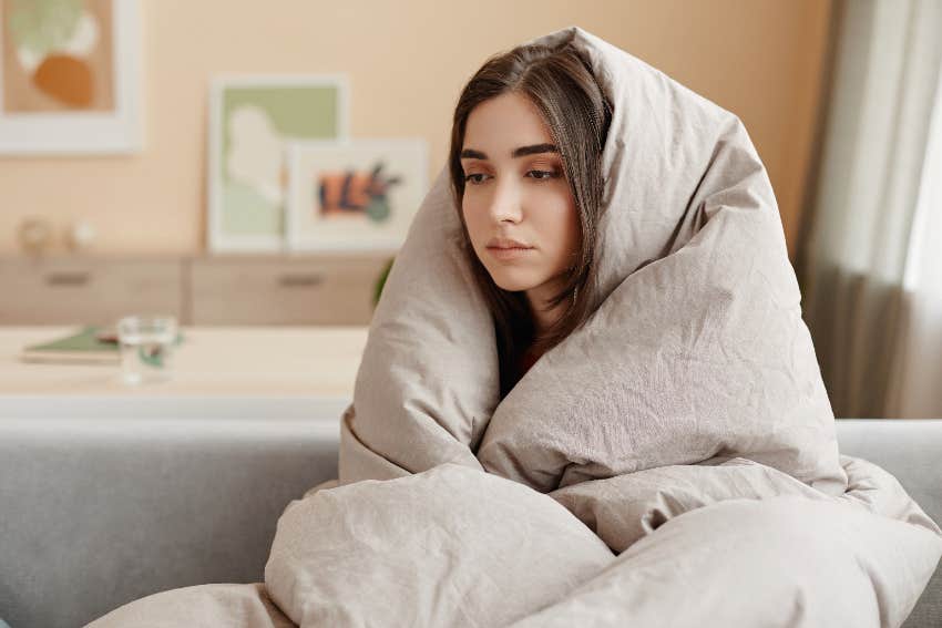 woman curled up in blanket looking sad