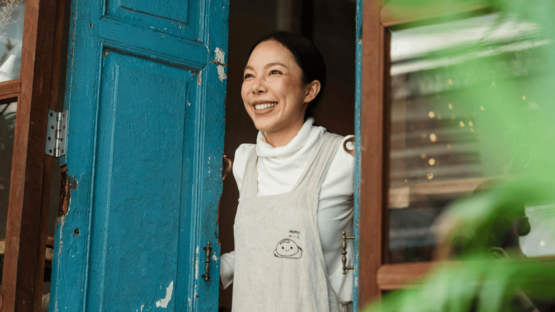 smiling woman peaking out from behind door