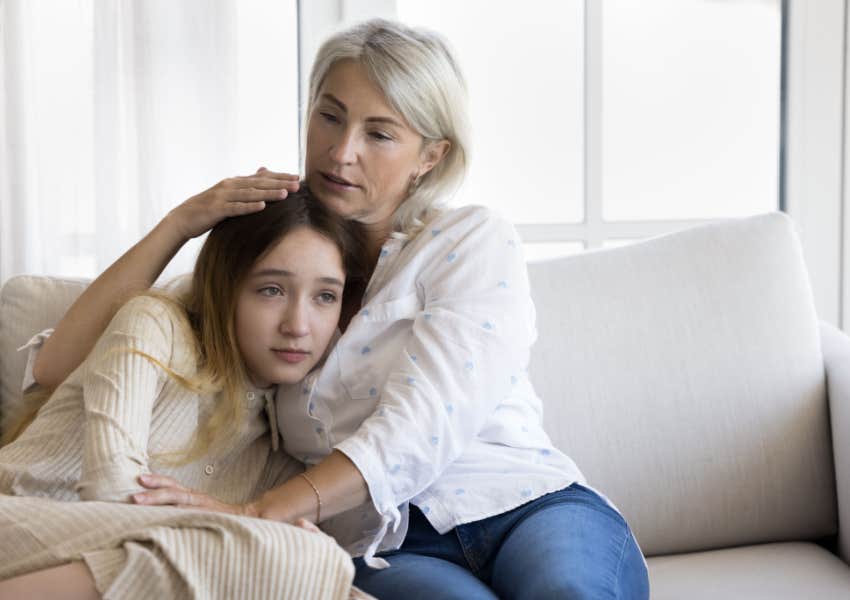 grandma comforts sad teen granddaughter on couch at home