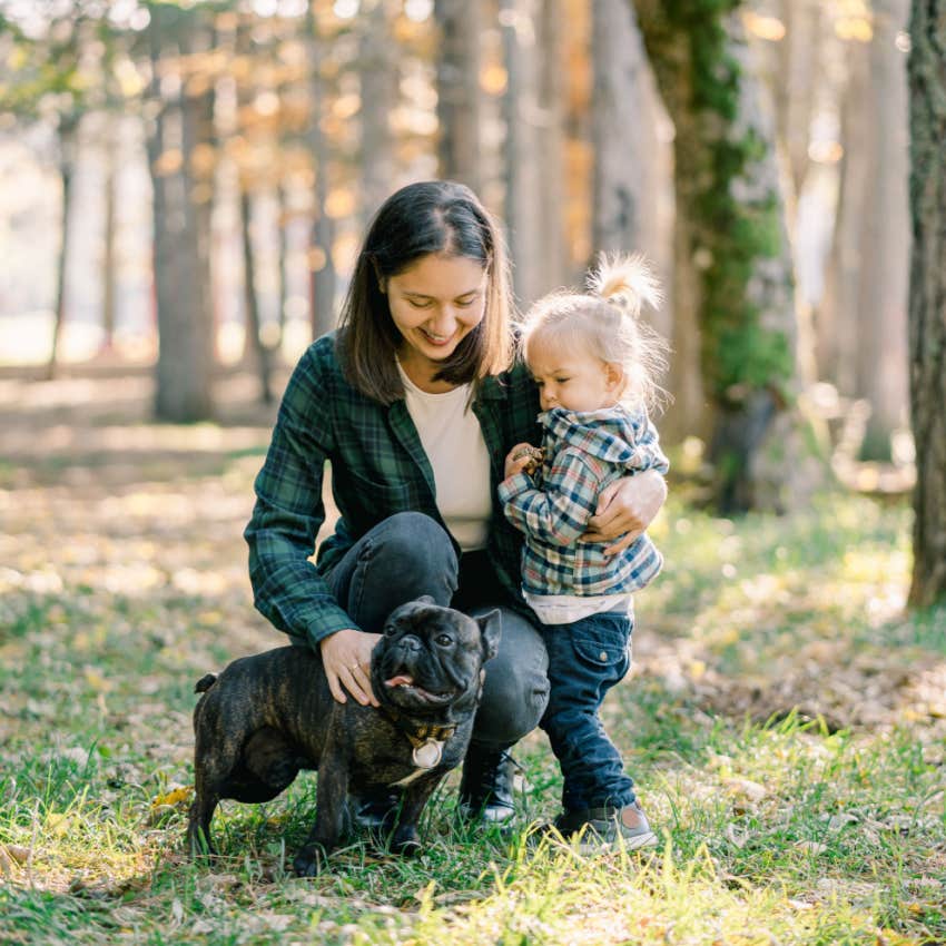 mom walking dog in forest with toddler