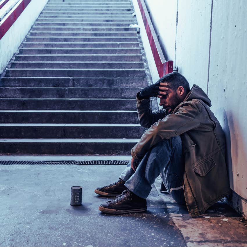 homeless man sitting at the bottom of subway steps