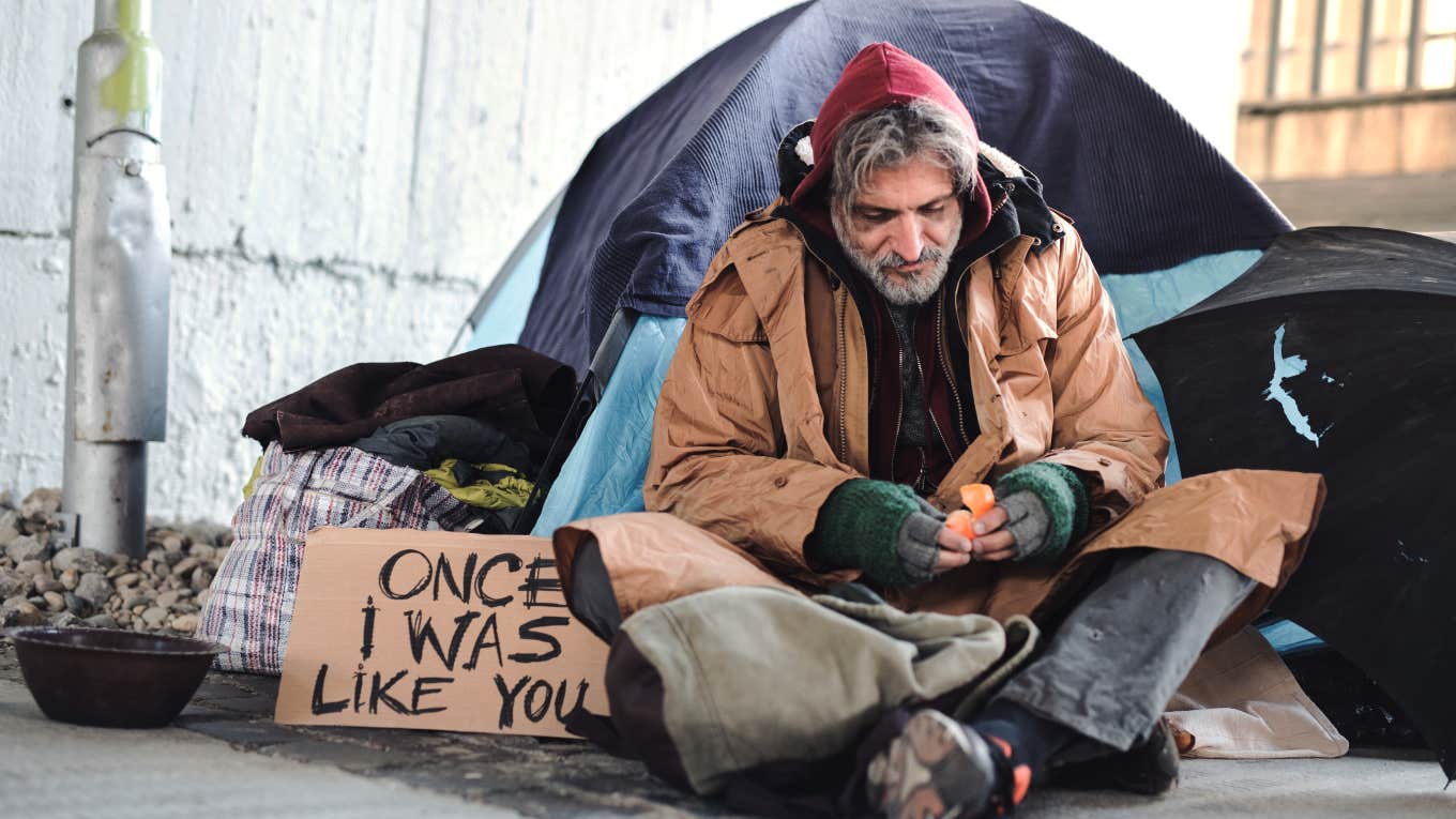 homeless man camped out with tent and sign