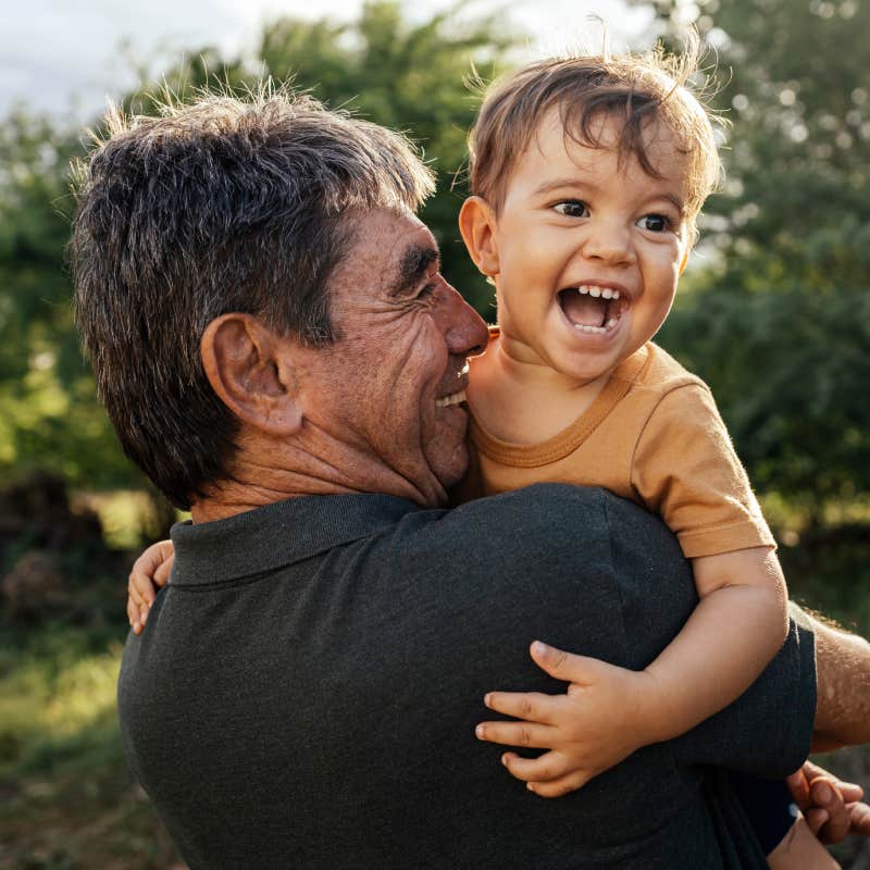 grandfather embracing smiling grandson outside