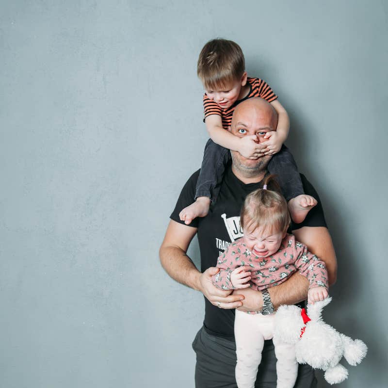 stressed young dad with two small children in his arms